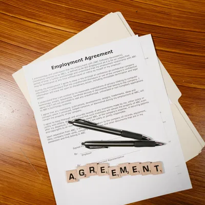 Napis AGREEMENT ułożony z klocków na dokumencie umowy