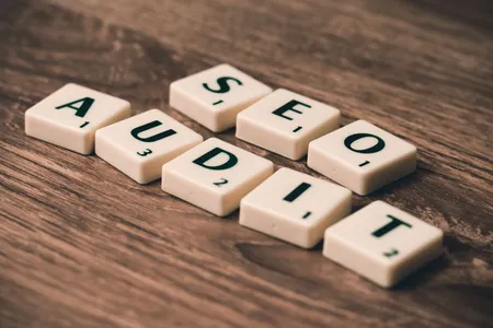 Napis SEO AUDIT ułożony z klocków na drewnianym blacie