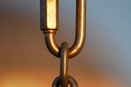 Zbliżenie metalowych ogniw łańcucha o zachodzie słońca, symbol linkowania