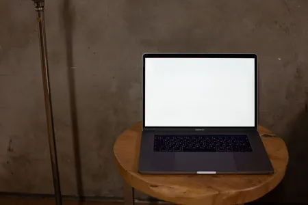 Laptop z jasnym ekranem na drewnianym stoliku w minimalistycznym wnętrzu